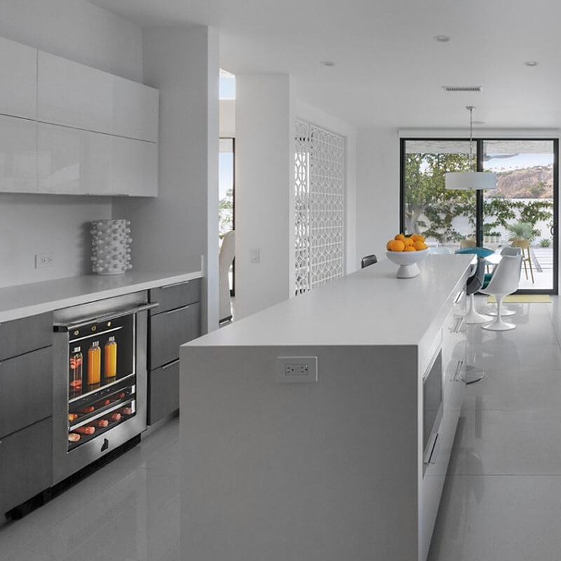 Open kitchen with green cabinetry, stone flooring, custom wood vent hood and a spacious dining table for entertaining.
