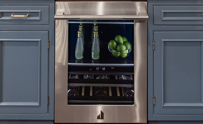 A built-in home bar with blue cabinets and an undercounter beverage center.