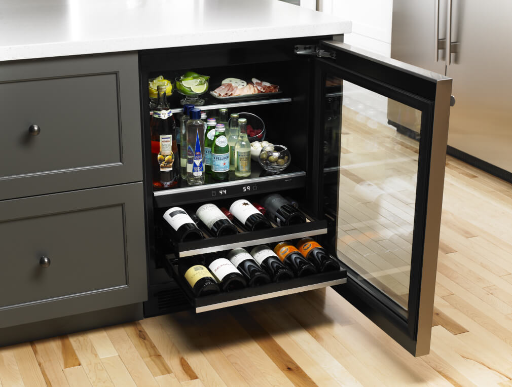 A mix of beverages, food and wine bottles displayed in a built-in beverage center.