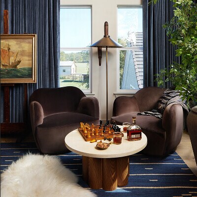 A room with blue curtains and two chairs placed in front of a chess set.