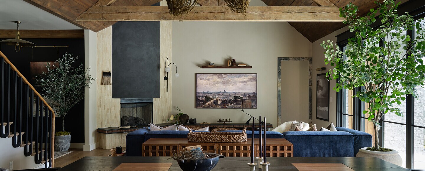 A living room with a blue couch, a fireplace and a brown credenza.