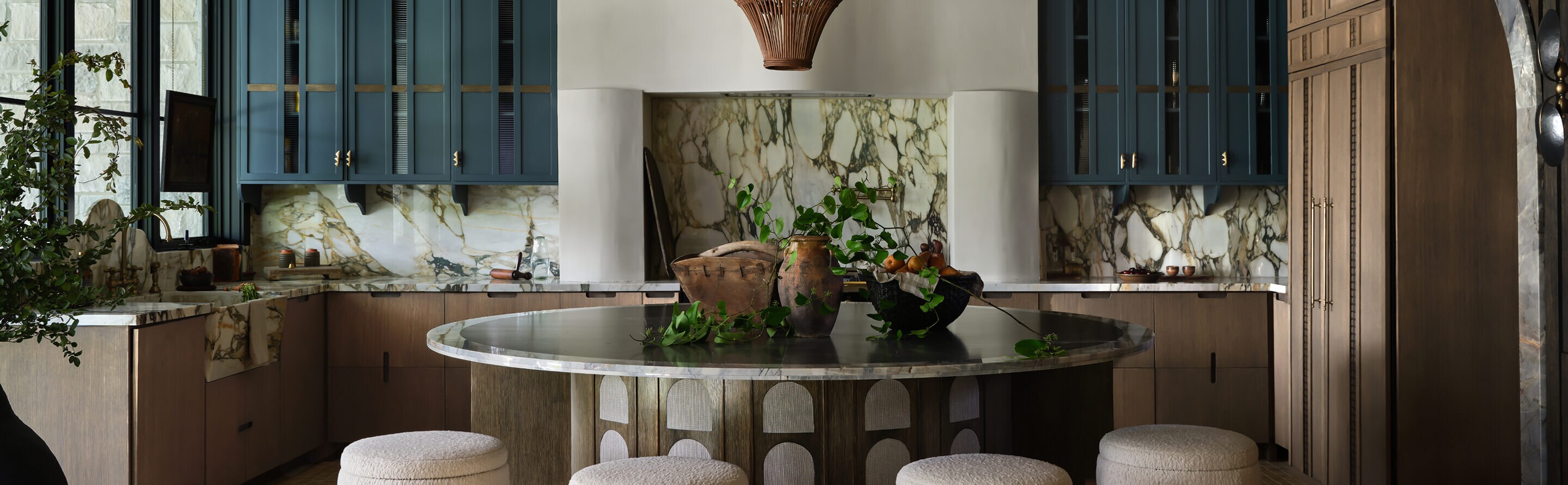 A kitchen with marble countertops and backsplash and a table with stools in the middle.