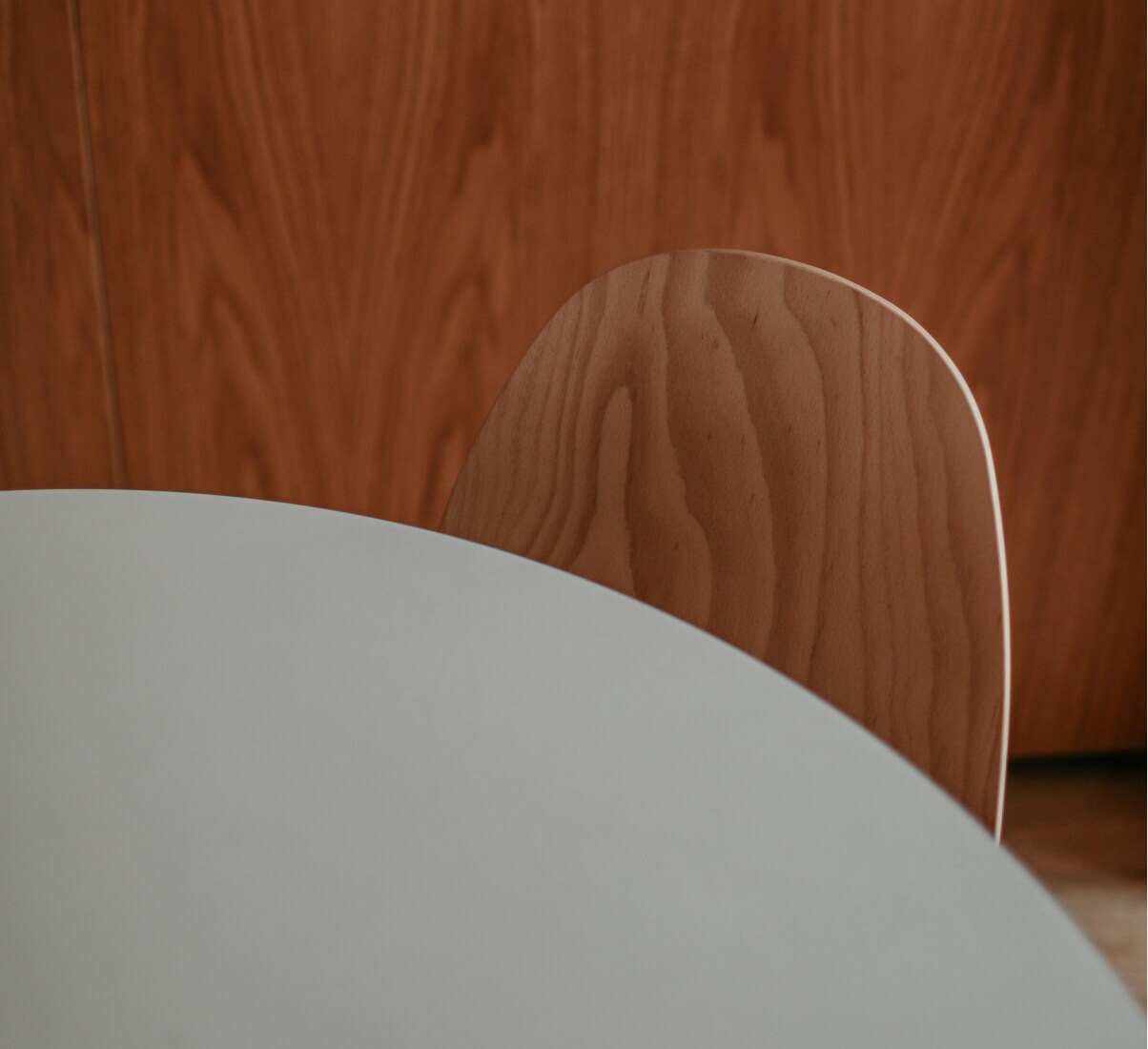 A close-up view of a white, round table with minimalist wood chairs.
