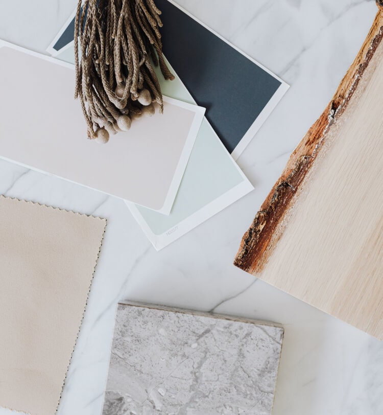 A contemporary luxury kitchen in white marble and light wood featuring a suite of JennAir® appliances.