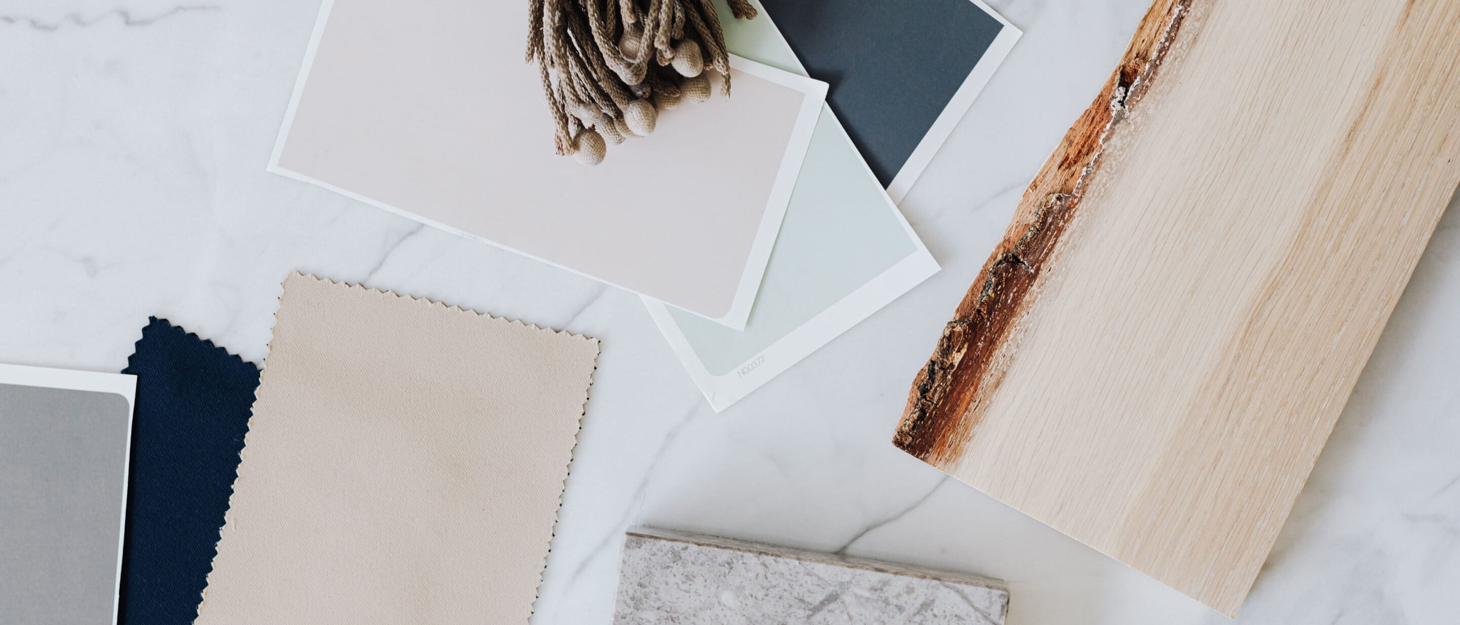 A series of swatches of soft colors, including beige, layered with wood, stone and other natural materials to form a pallet.