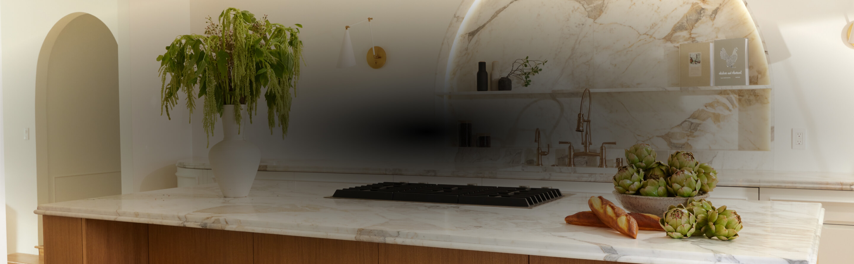 A white and light wood kitchen with a marble backsplash, designed by Nina Takesh.