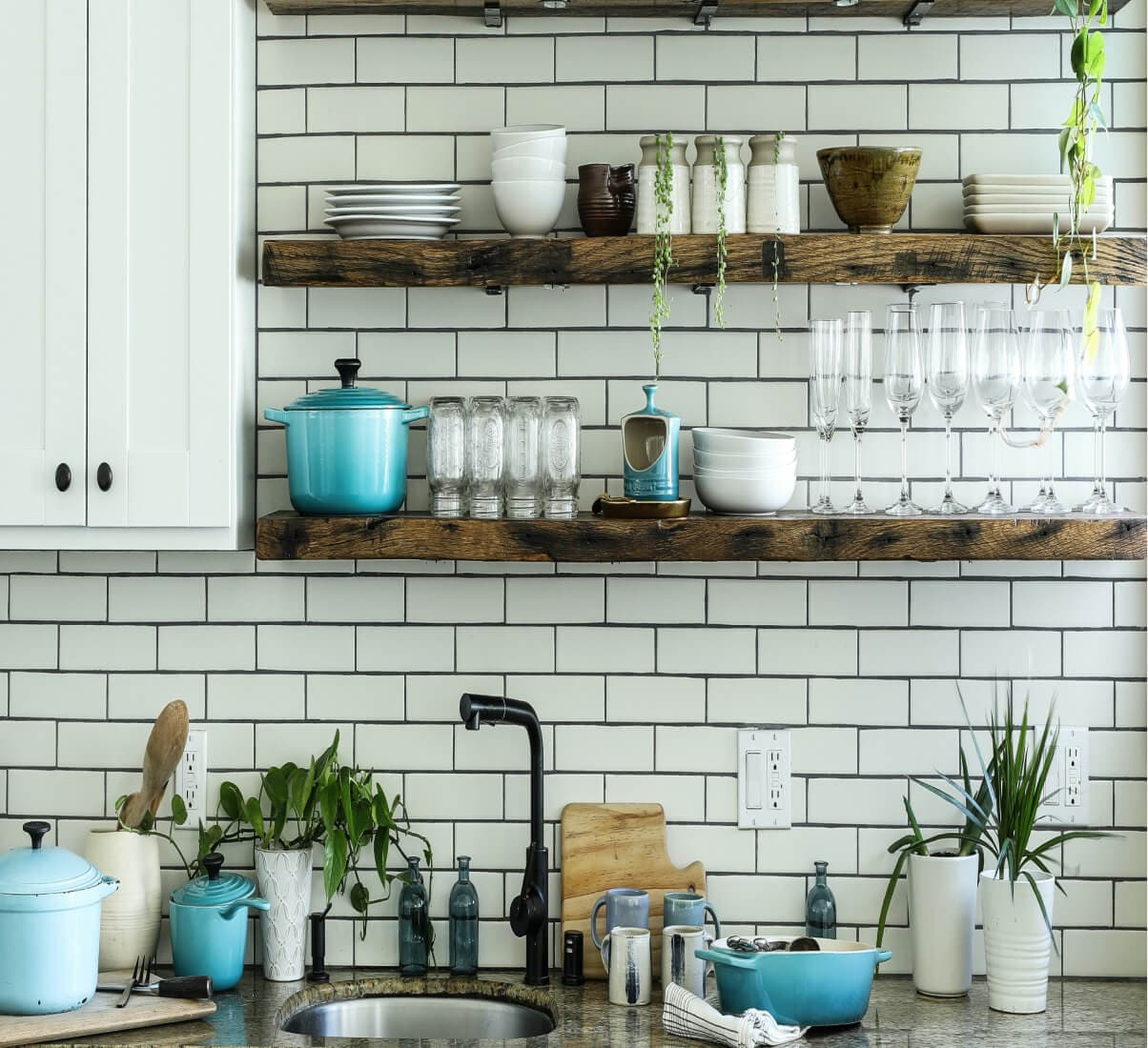 A close-up of a white subway tile kitchen with open shelving.
