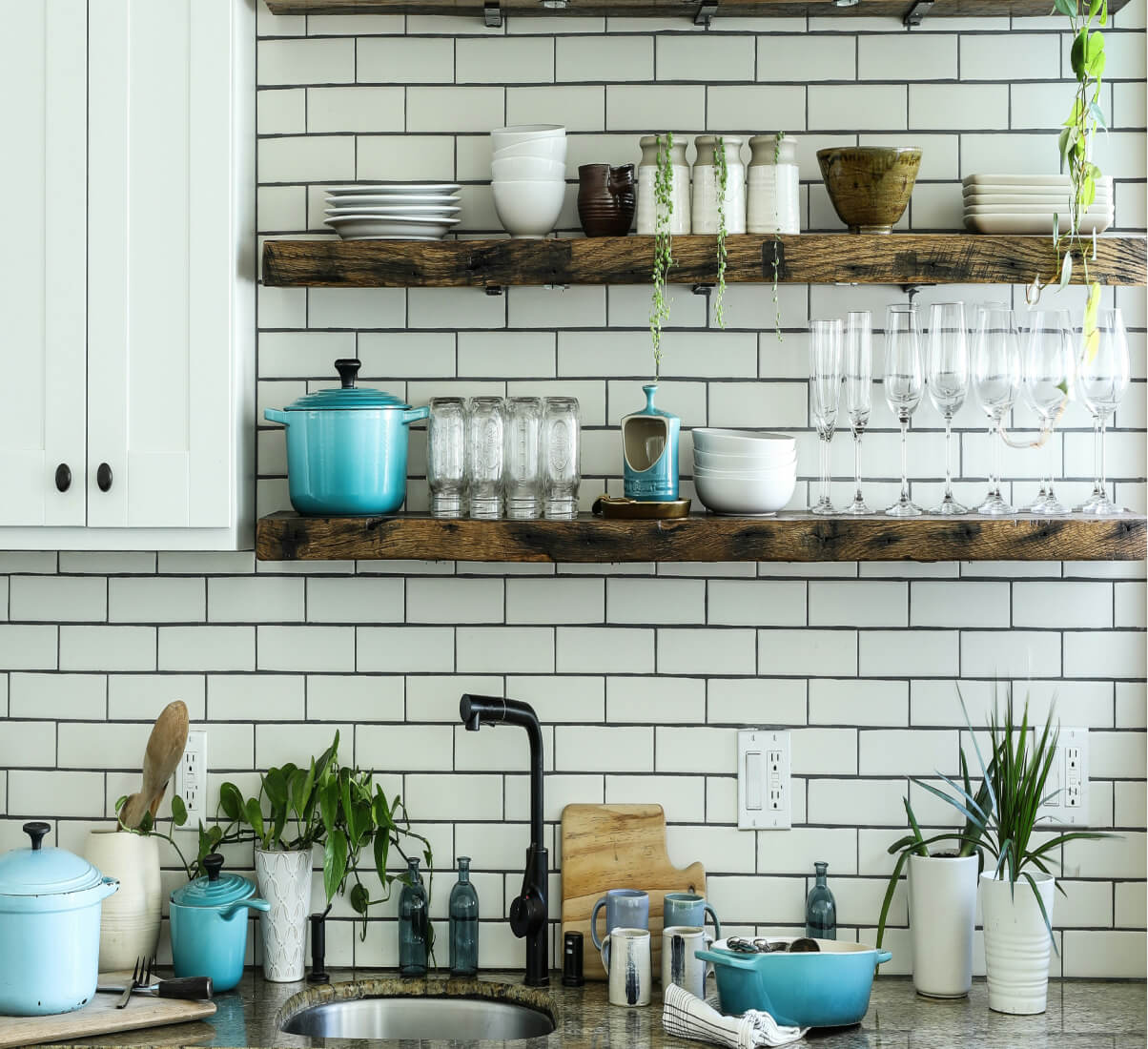 A close-up of a white subway tile kitchen with open shelving. A close-up of a white subway tile kitchen with open shelving.