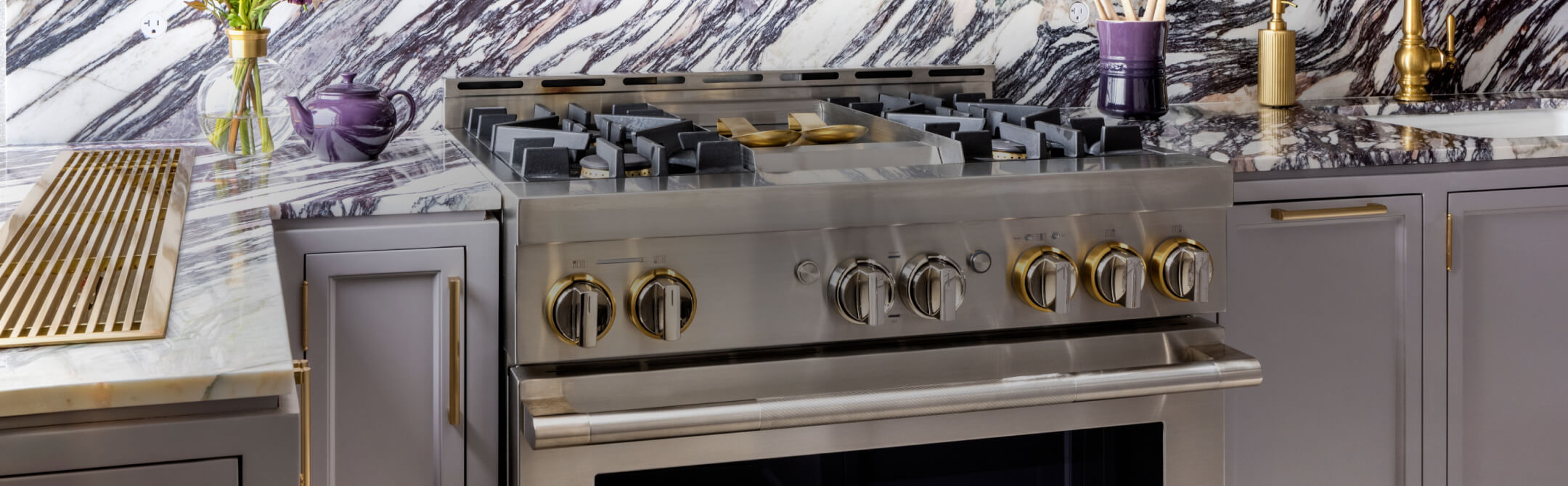 A JennAir® RISE™ Range in a white marble kitchen.