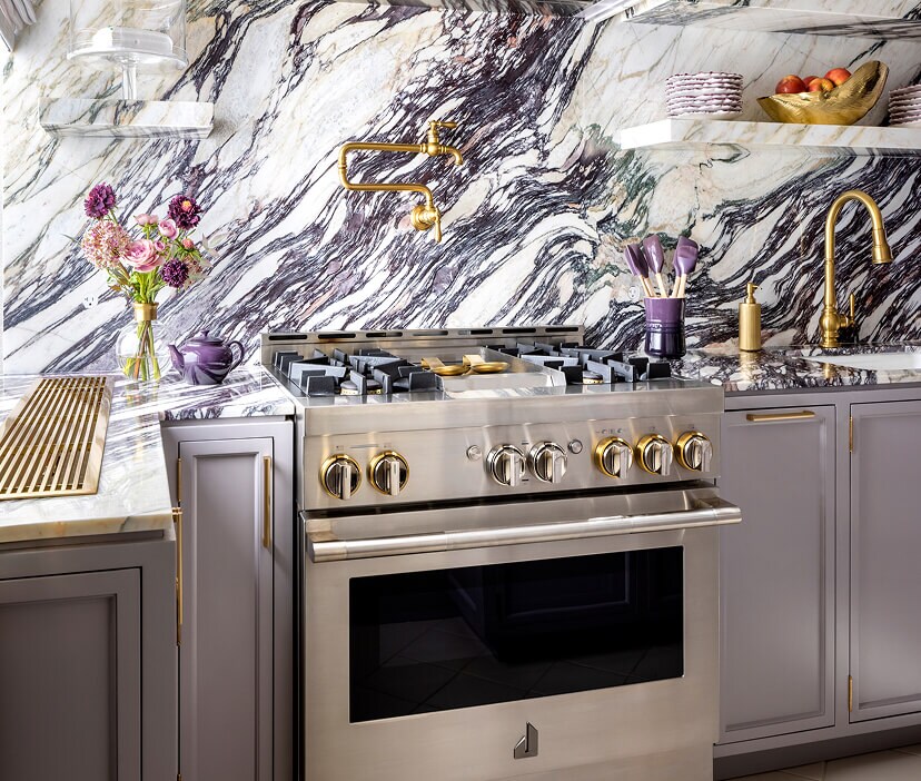 A JennAir® RISE™ Range in a white marble kitchen.