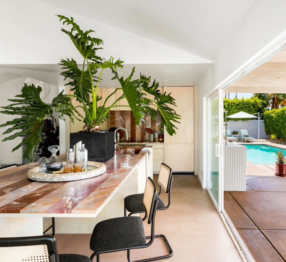 The kitchen of the Palm Springs home, showing a large plan on the island and chairs along the island.