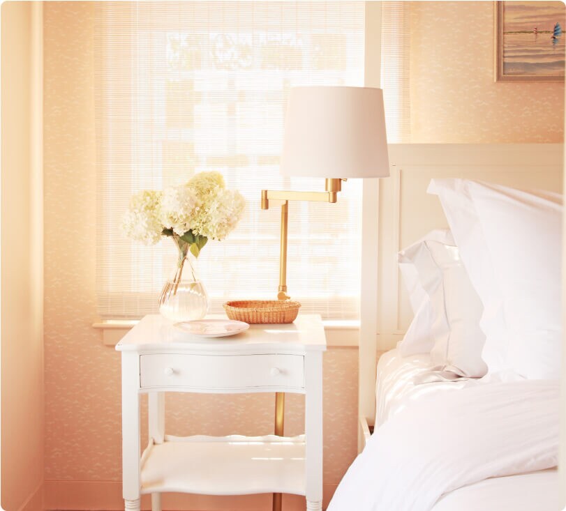 The nightstand decorated with hydrangeas and other dishes next to the bed. 