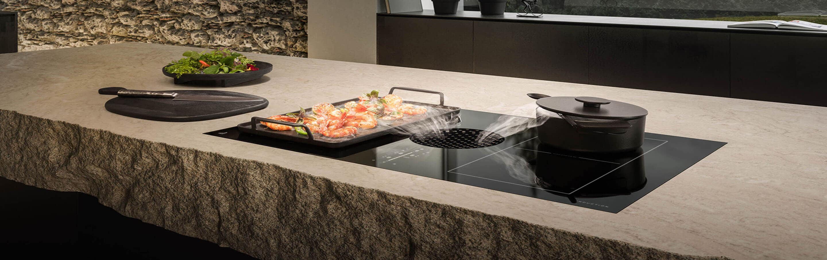 A quiet induction downdraft cooktop ventilates cooking fumes in a luxury kitchen