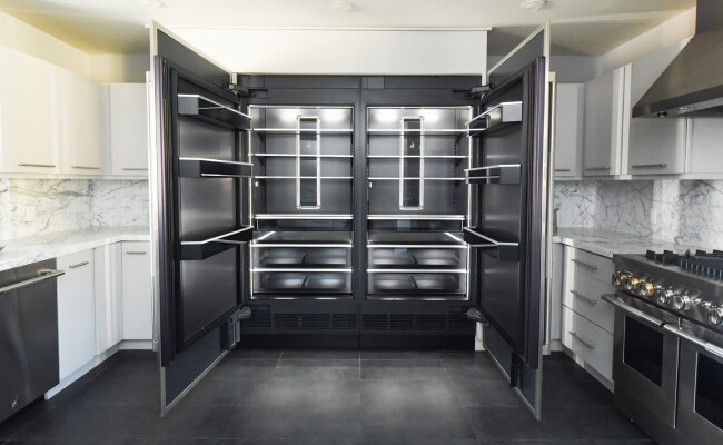 A bold, modern kitchen with an open JennAir® Refrigerator showcasing the Daring Obsidian Interior.