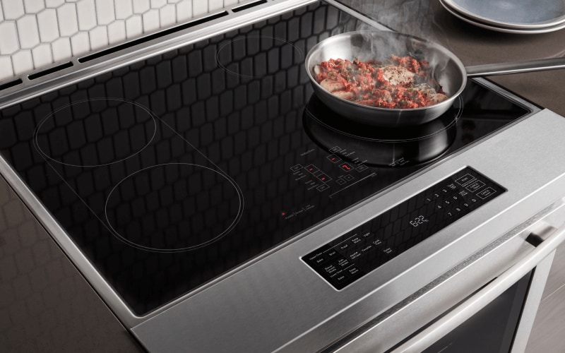 Fresh ingredients being cooked on an induction cooktop on a range.