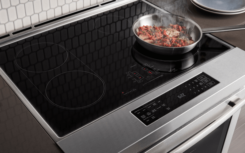 Fresh ingredients being cooked on an induction cooktop on a range. Fresh ingredients being cooked on an induction cooktop on a range.
