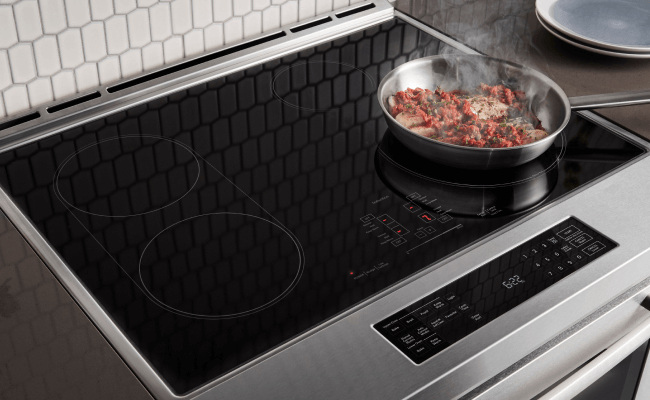 Fresh ingredients being cooked on an induction cooktop on a range. Fresh ingredients being cooked on an induction cooktop on a range.