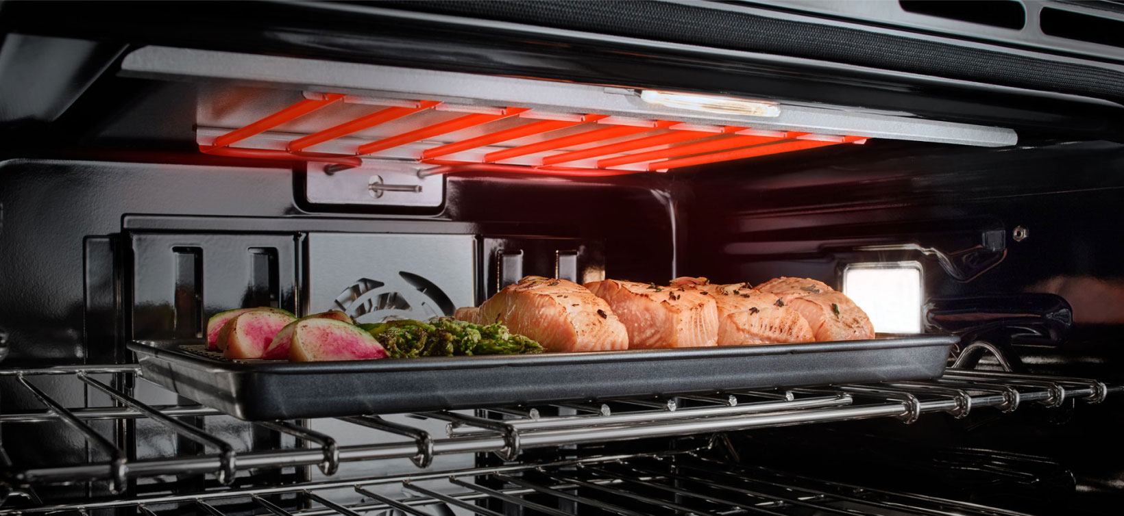 Salmon, asparagus and other vegetables cooking in a JennAir Wall Oven. 