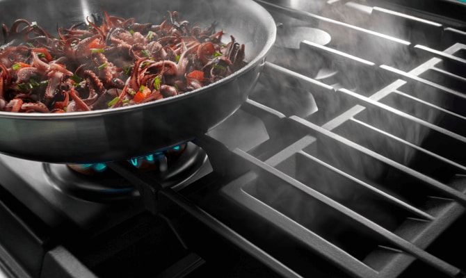 Food cooking on a gas cooktop with downdraft ventilation