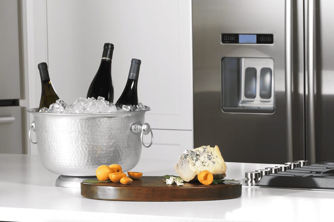 Wine bottles chilling in ice on a kitchen island.