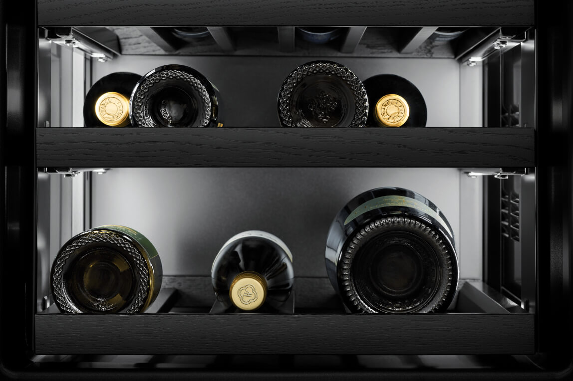 A wine refrigerator with wine bottles stored horizontally.