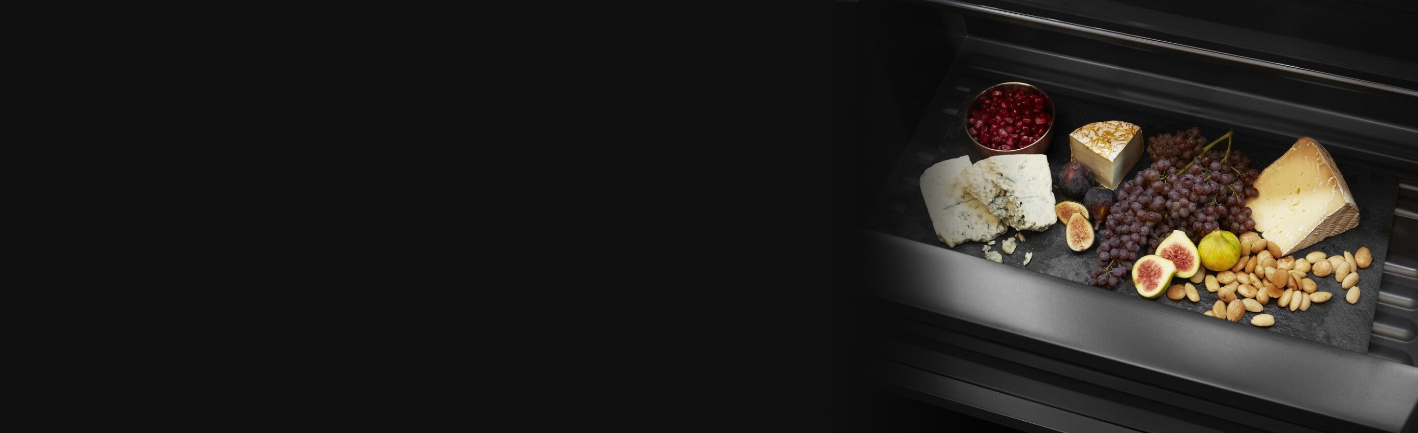 An open built-in refrigerator and a drawer holding a charcuterie board. 