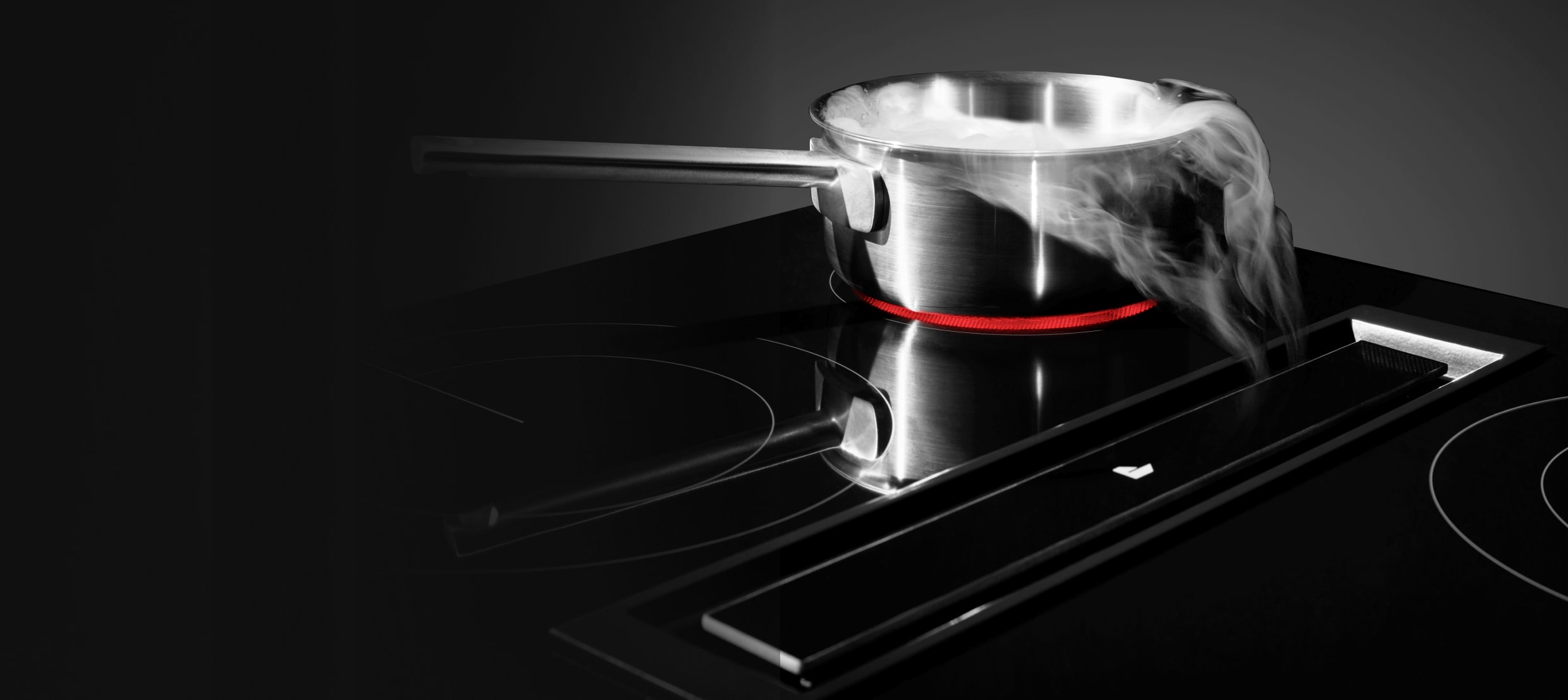  A JennAir® Downdraft Electric Cooktop pulling steam into the vent.