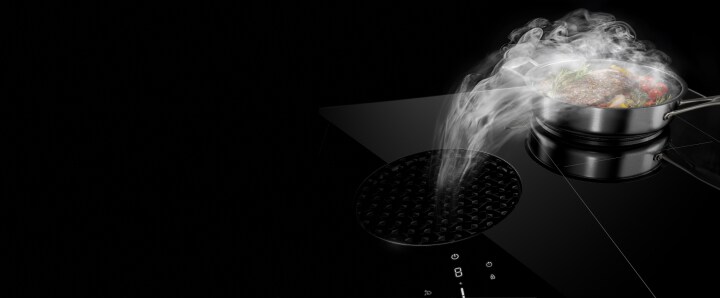 A pan on a downdraft cooktop with the steam pulling into the center vent.