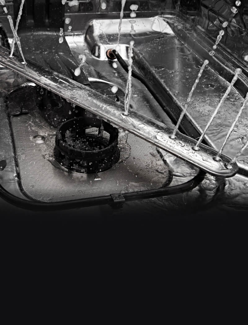 Stainless steel wash arms spraying water in a dishwasher.