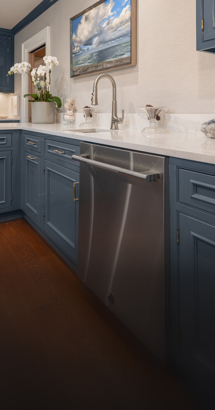A JennAir® RISE™ Dishwasher in a kitchen with blue cabinets.