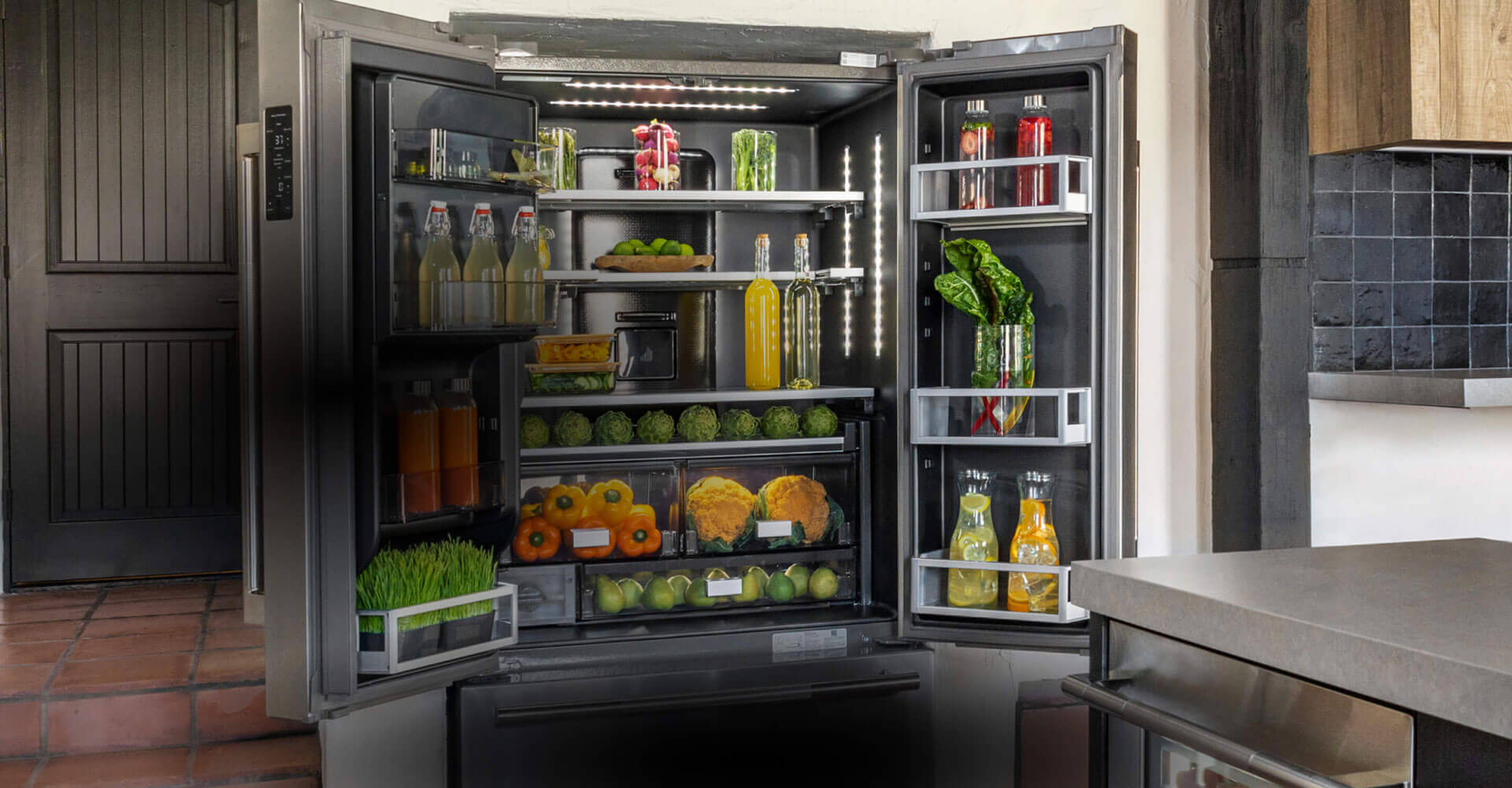An open JennAir® french door freestanding refrigerator, fully stocked with vibrant, colorful produce and ingredients. 