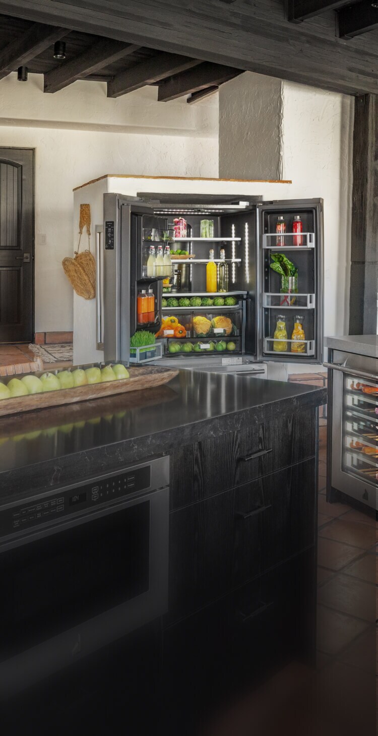 A kitchen featuring an open and stocked JennAir® French Door Freestanding Refrigerator.