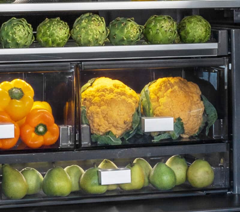 The interior of a freestanding refrigerator filled with vibrant foods and ingredients.