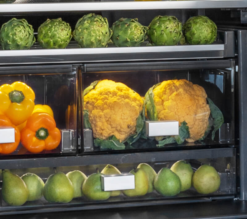 The interior of a freestanding refrigerator filled with vibrant foods and ingredients.