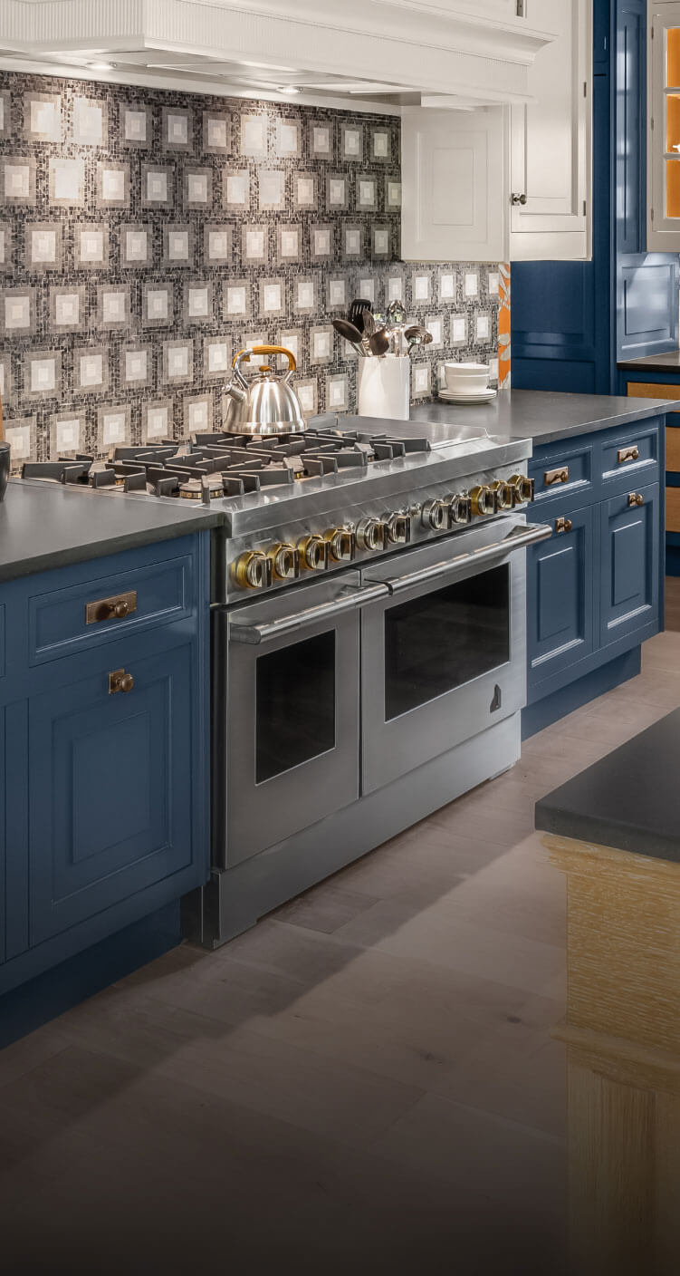 A JennAir® RISE™ Dual-Fuel Range in a blue luxury kitchen.