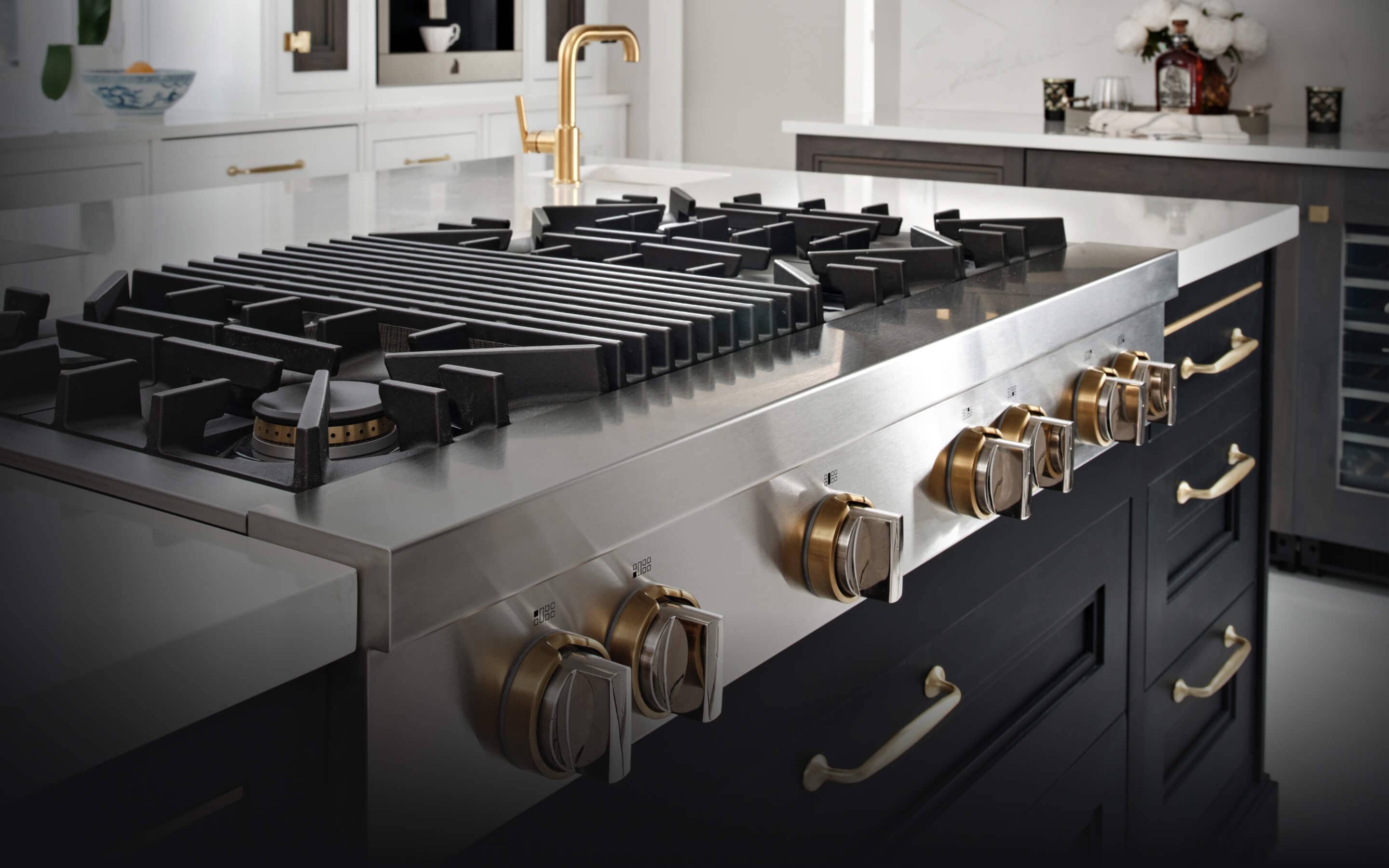 A JennAir® Gas Rangetop in a kitchen with dark cabinets and brass accents.