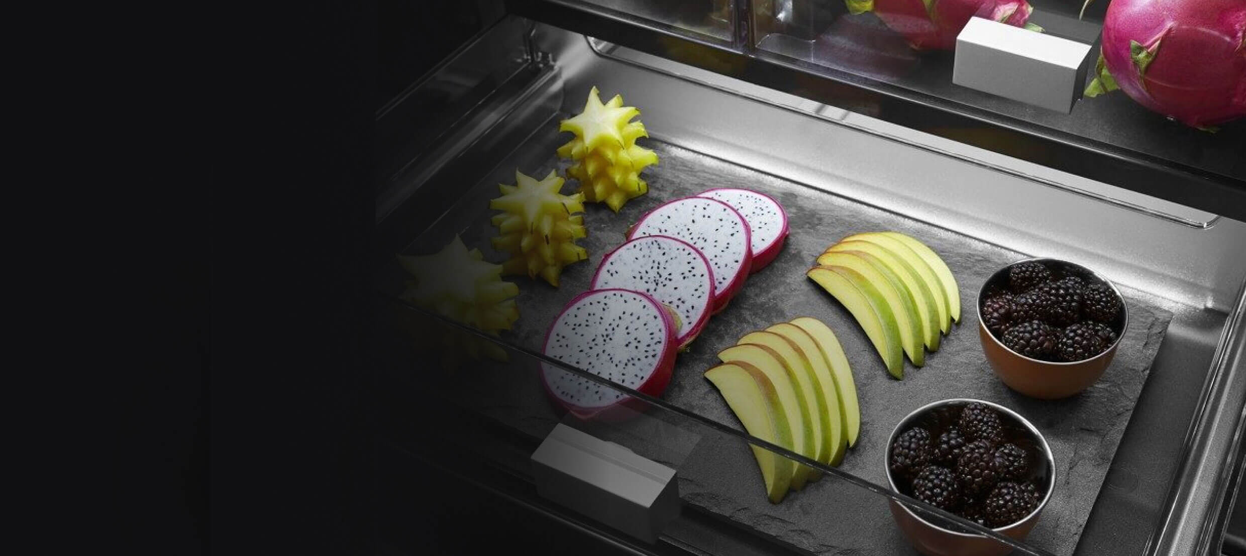 The interior of a full-width drawer filled with various fruits.