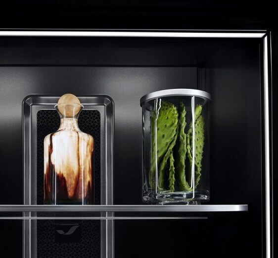 A close-up of shelves in a JennAir® Refrigerator, showing Ecliptic Lighting against the Obsidian Interior.