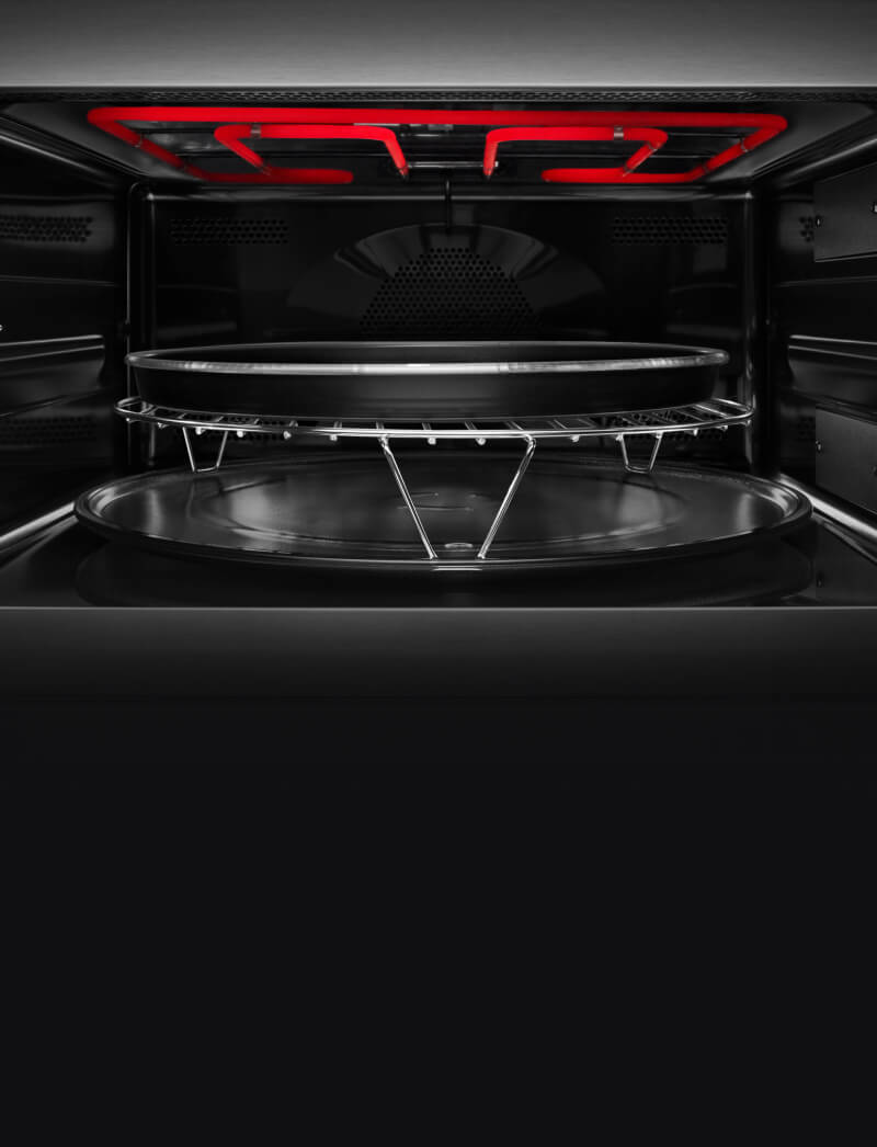 A crisp pan inside a microwave with the upper heating element lit up.