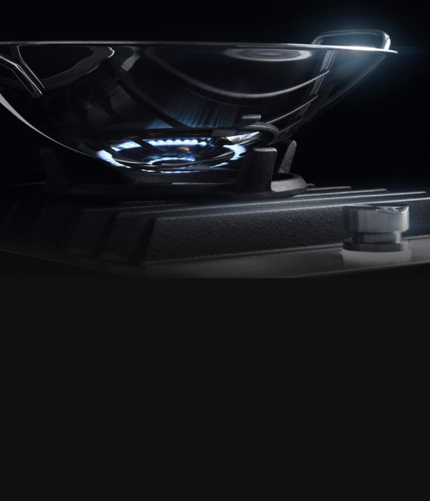 The wok ring on the cooktop, with a stainless steel wok on top.