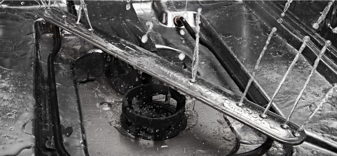 The interior of a JennAir® dishwasher, water spraying from the spray arms.