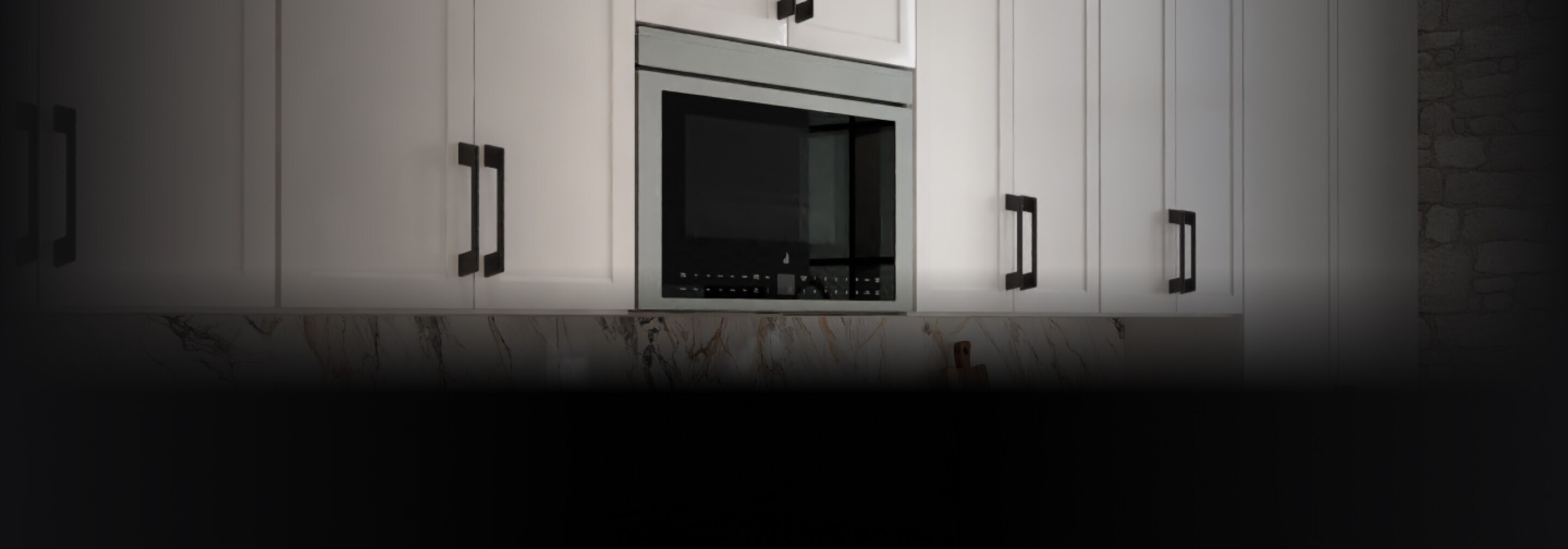 A flush oven hood microwave installed in a bank of white upper cabinets.