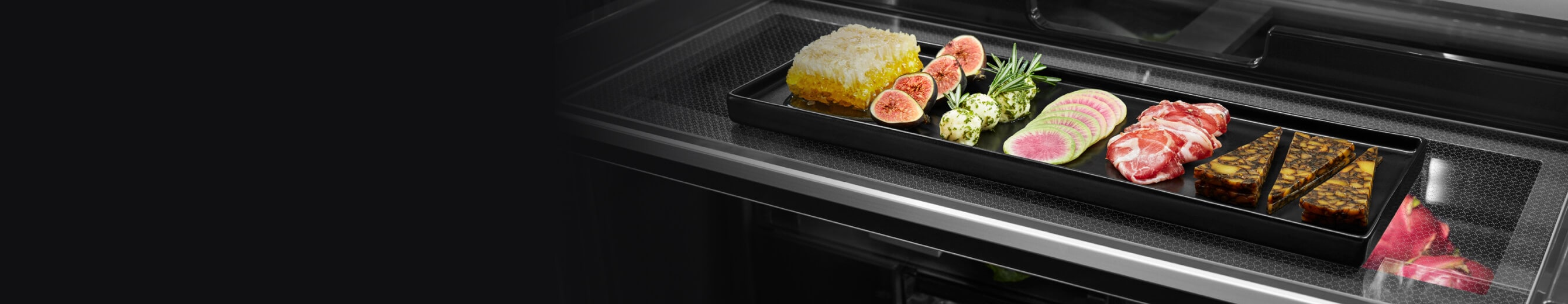 A charcuterie tray on a full-length shelf in a freestanding refrigerator.