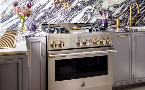 A JennAir® RISE™ Range in a white marble kitchen.