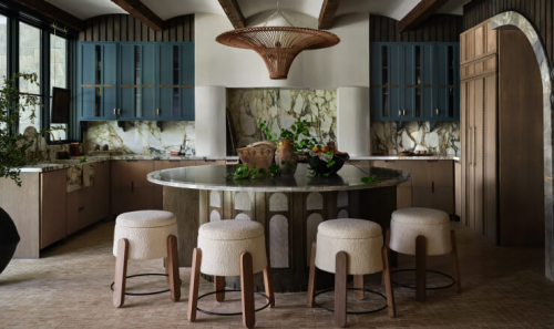 A kitchen with marble countertops and backsplash and a table with stools in the middle.