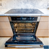 An open JennAir® wall oven installed below an induction cooktop