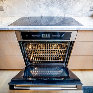 An open JennAir® wall oven installed below an induction cooktop