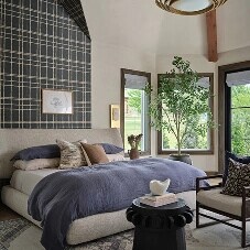 A bedroom with a partially wallpapered wall