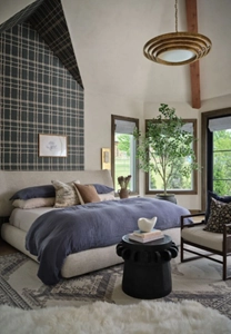 A bedroom with a partially wallpapered wall