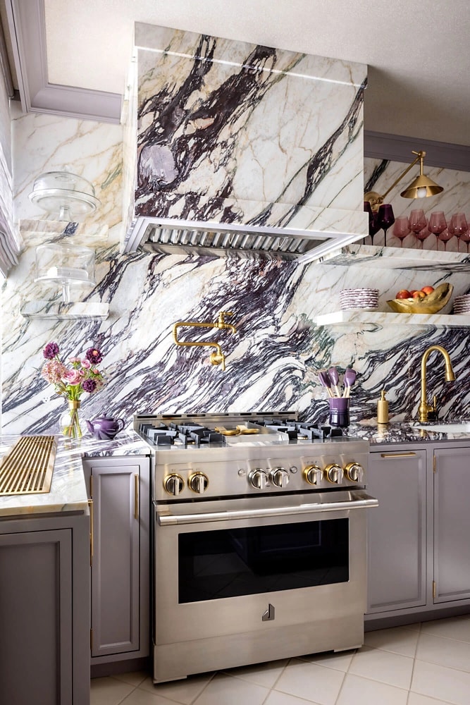 A close up on a JennAir® range in a marble kitchen.